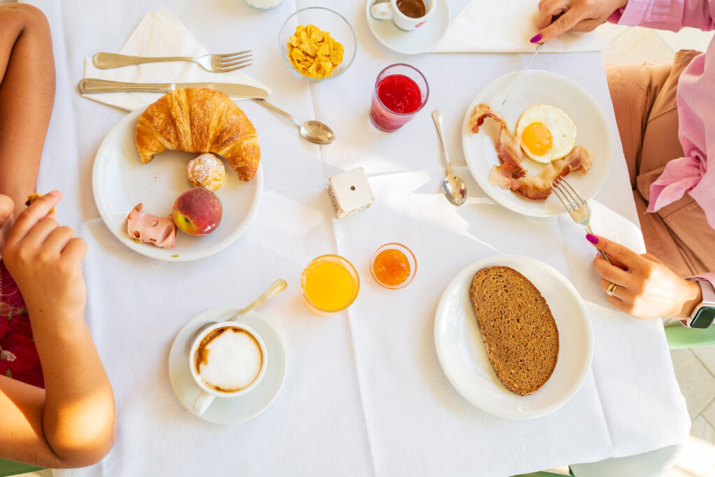 Galleria - Due persone che fanno colazione all'Hotel Domus de Janas una con pietanze dolci l'altro con cibi salati