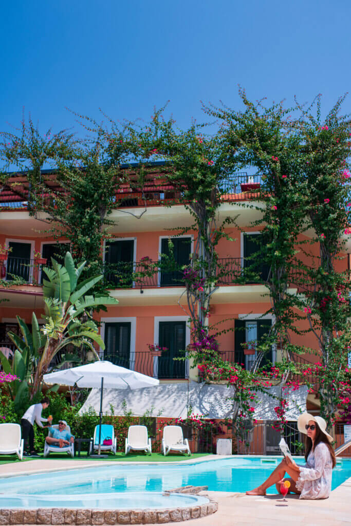 Galleria - Vista della piscina dell'Hotel Domus de Janas con una ragazza che legge un libro