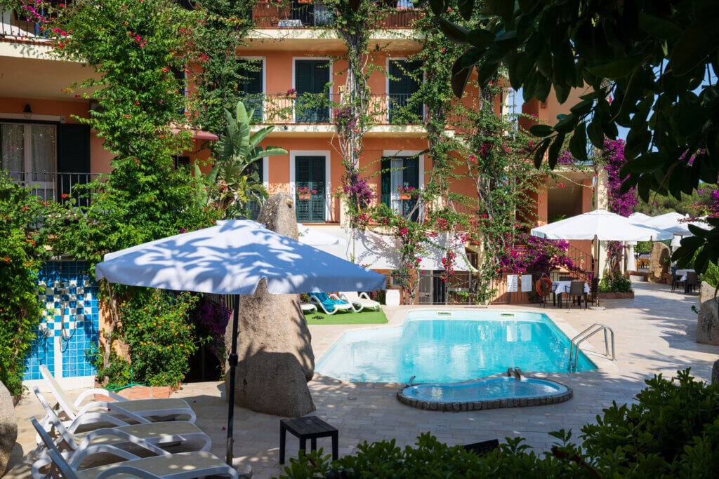 Galleria - Piscina dell'Hotel Domus de Janas con lettini ed ombrelloni