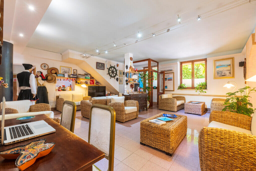 Galleria - La Hall dell'Hotel Domus de Janas con arredamento in paglia e decorazioni tipiche della Sardegna