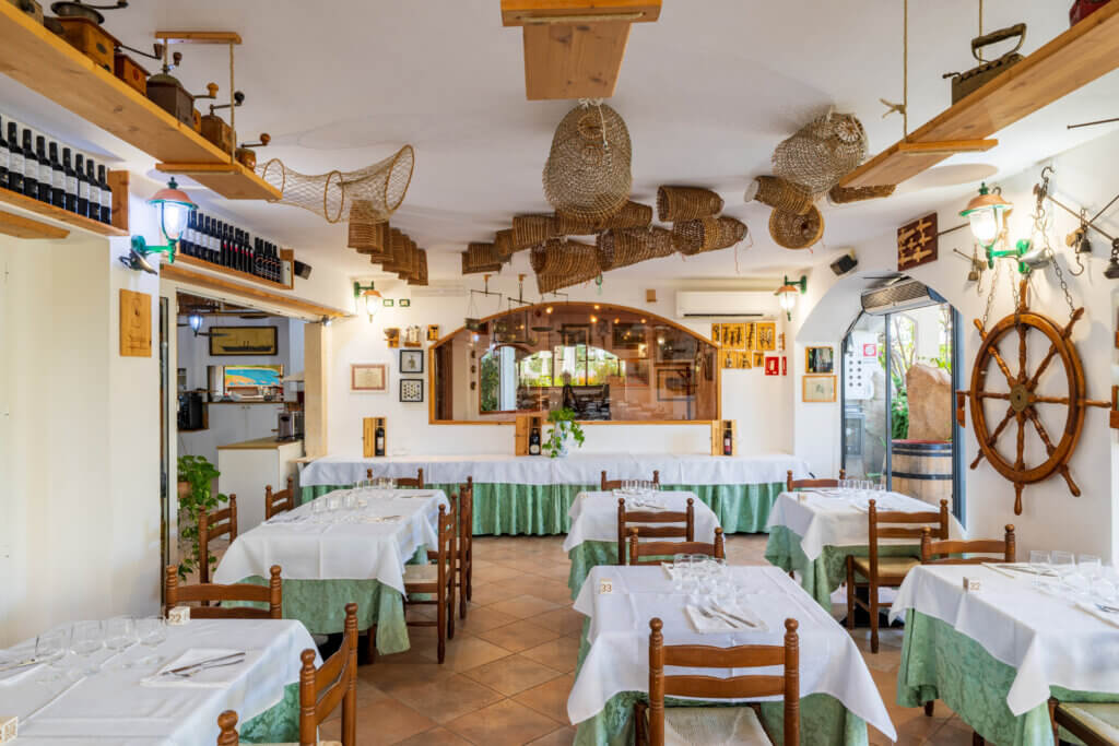 Galleria - Vista della sala interna del ristorante Il Pesciolino dell'Hotel Domus de Janas decorata da vecchie trappole di pescatori
