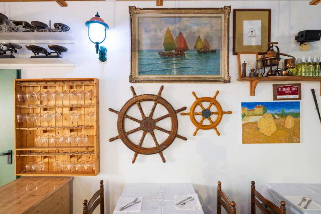 Galleria - Particolare della sala interna del ristorante Il Pesciolino dell'Hotel Domus de Janas con decorazioni create da due timoni di barca